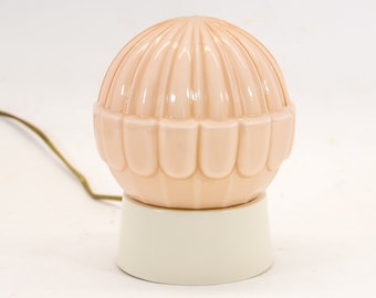 May include: A pink glass table lamp with a scalloped design and a white base.