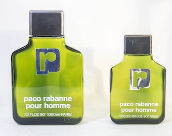 May include: Two green glass bottles of Paco Rabanne Pour Homme cologne. The bottles have a silver cap and a silver and blue logo. The larger bottle reads "32 FLOZ 90° 1000ml PARIS". The smaller bottle reads "500ml 16FLOZ 90° PARIS".