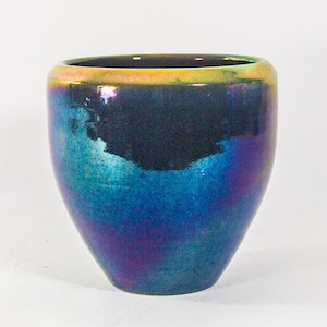 Könnte beinhalten: Ein kleiner, irisierender blauer und schwarzer Keramiktopf mit goldfarbenem Rand.