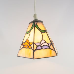Könnte beinhalten: Eine Tiffany-Hängelampe mit einem pyramidenförmigen Schirm. Der Schirm hat ein florales Design mit orangefarbenen, violetten und grünen Akzenten.