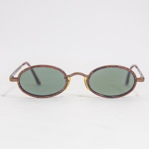May include: A pair of oval-shaped sunglasses with brown frames and green lenses.