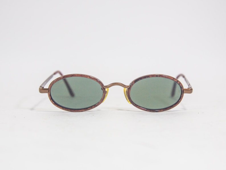May include: A pair of oval-shaped sunglasses with brown frames and green lenses.