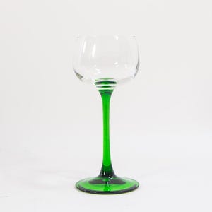May include: A clear glass wine glass with a green stem and base. The glass has a rounded bowl and a wide base.