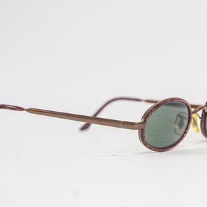May include: Brown metal framed oval sunglasses with green lenses.