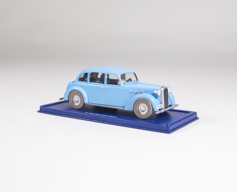 May include: A light blue toy car model with a black base and the text "27 ROYALE AUTOMOBILES" on the base. The car has a number plate that reads "FN-301".