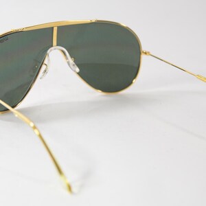 May include: Gold aviator sunglasses with green lenses. The sunglasses have a thin gold frame and a gold nose bridge.