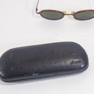 May include: A black leather Ray-Ban sunglasses case with the brand name embossed on the front.