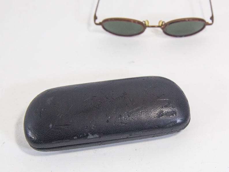 May include: A black leather Ray-Ban sunglasses case with the brand name embossed on the front.
