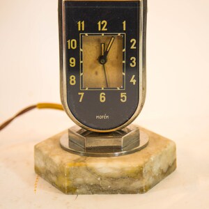 Peut inclure: Un r&eacute;veil vintage argent&eacute; et noir avec une base en marbre. Le cadran de l'horloge a des chiffres et des aiguilles dor&eacute;s. L'horloge est fabriqu&eacute;e par la soci&eacute;t&eacute; "Mof&eacute;m".