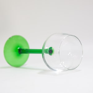 May include: A wine glass with a green stem and a clear bowl. The stem is a solid green colour and the bowl is clear glass.