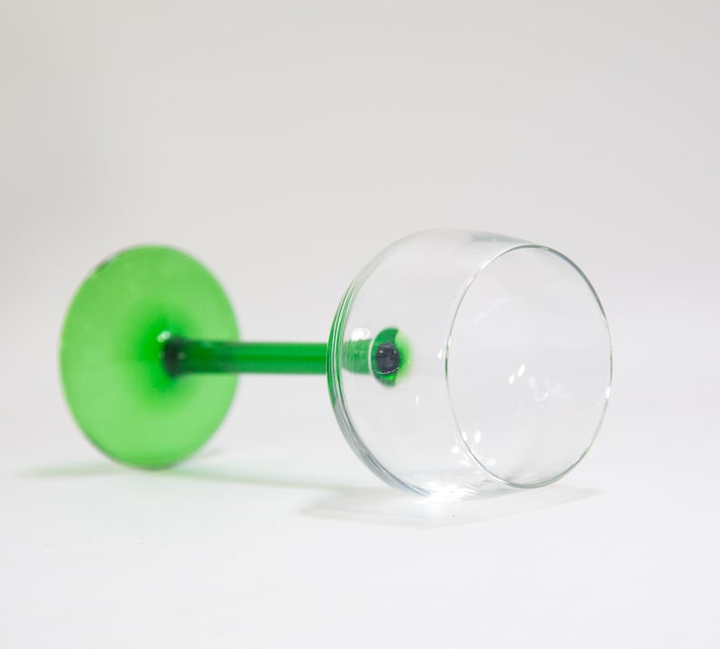 May include: A wine glass with a green stem and a clear bowl. The stem is a solid green colour and the bowl is clear glass.