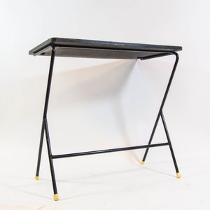 May include: A black metal side table with a rectangular wooden top and gold-coloured tips on the legs.