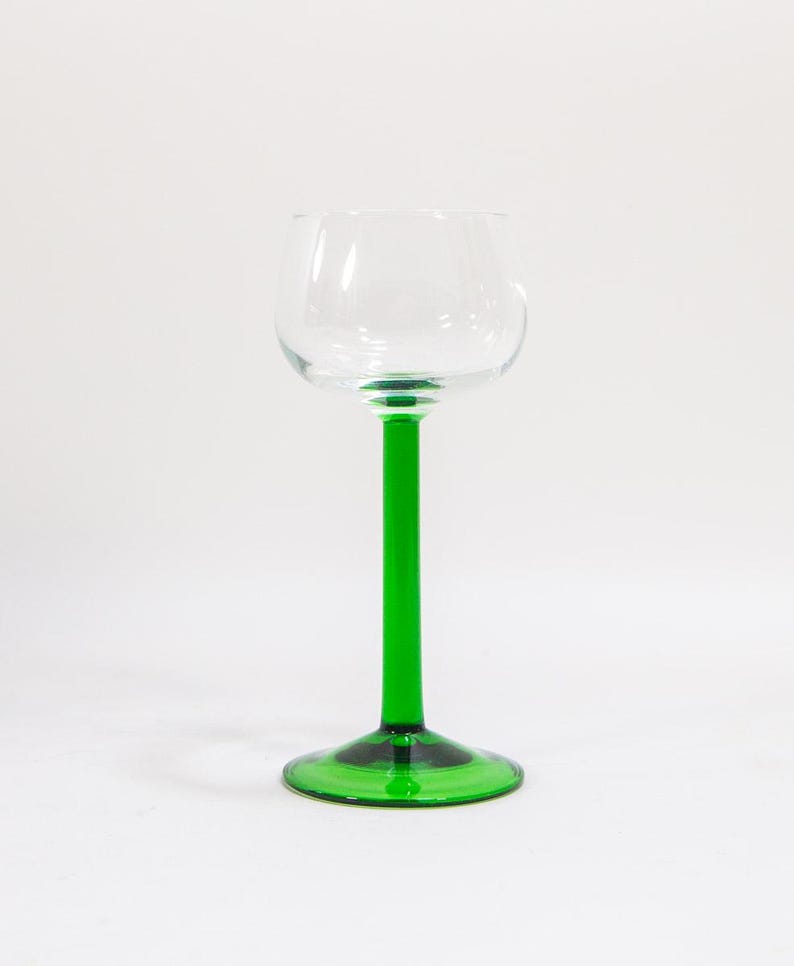 May include: A tall, clear glass with a green stem and base. The glass is designed for drinking wine or other beverages.