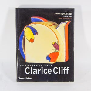 Puede incluir: Un libro titulado "Comprehensively Clarice Cliff" con una cubierta negra. La portada presenta una ilustración colorida de una pieza de cerámica con detalles en amarillo, azul y naranja. El texto "OVER 2000 CERAMIC PIECES, PATTERNS AND BACKSTAMPS" es visible.