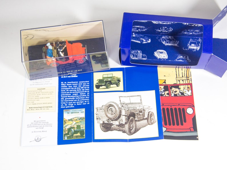 May include: A red toy jeep in a clear display case. The jeep has two figures inside. The case is on a blue and white background with text that reads 'The Universal Jeep' and 'All the Facts of the War'.