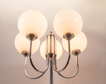 May include: A chrome floor lamp with five white globe-shaped light shades. The lamp has a modern design with curved arms.