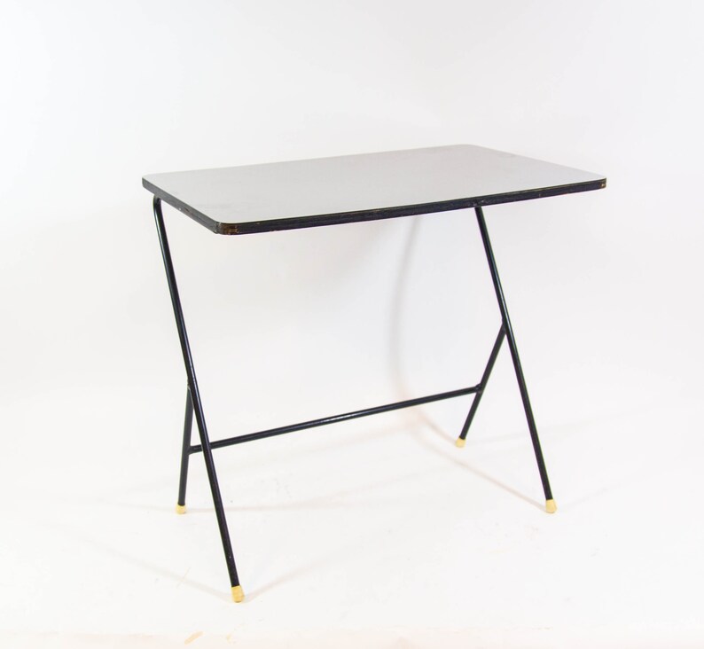 May include: A black metal table with a white laminate top. The table has a simple, modern design with a single shelf.