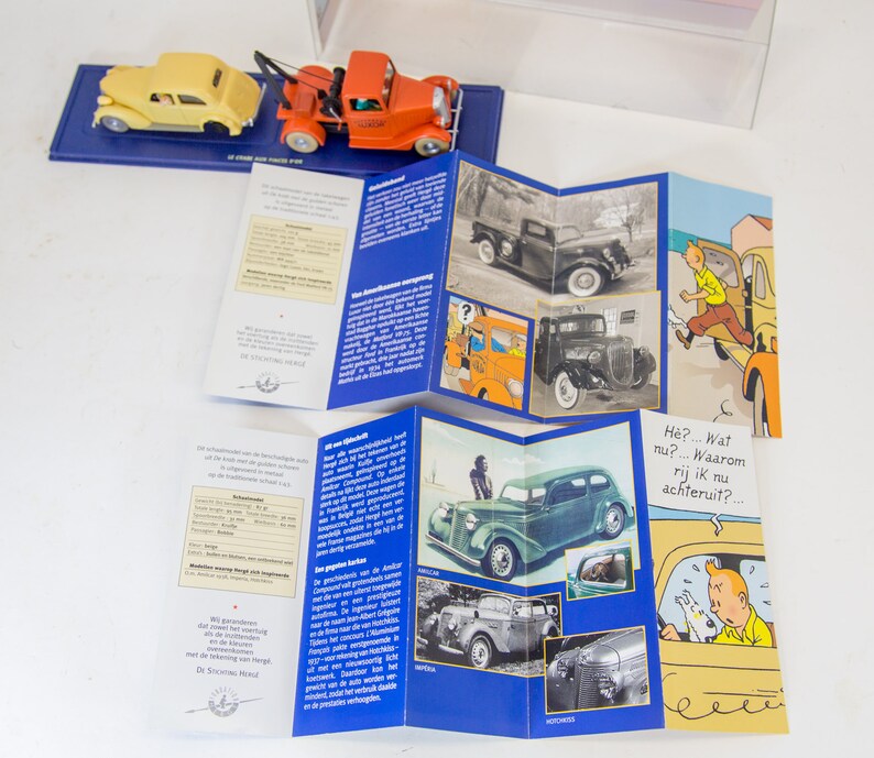 Puede incluir: Un folleto de varios paneles con ilustraciones de coches antiguos y personajes de dibujos animados. El folleto presenta una combinaci&oacute;n de colores rojo, blanco y azul e incluye texto en holand&eacute;s. El texto dice "De Stroomlijn Wereld" y "H&eacute;? ... Wat nu? ... Waarom rij ik nu achteruit? ..."