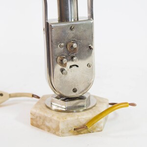 Peut inclure: Une lampe de table en argent et chrome avec une base en marbre et un cordon avec un fil jaune. La lampe a une base ronde en argent et une tige en chrome avec un abat-jour en argent.