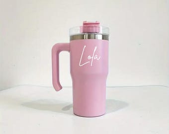 May include: A pink stainless steel travel mug with a handle and a lid. The mug has the name "Lola" written on it in white.
