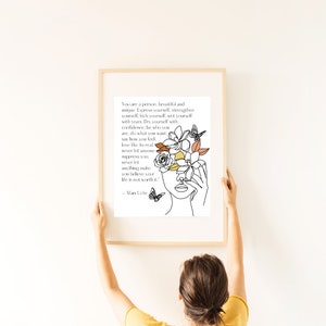 Puede incluir: Un dibujo en blanco y negro de una cara de mujer con flores que le cubren los ojos. La cita "You are a person, beautiful and unique. Express yourself, strengthen yourself, kick yourself, wet yourself with tears. Dry yourself with confidence, be who you are, do what you want, say how you feel, love like it's real. Never let anyone suppress you. Never let anything make you believe your life is not worth it." - Afam Uche está impresa debajo del dibujo.