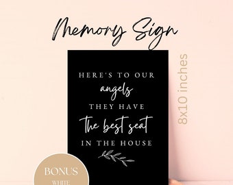 May include: Black and white sign with the text "Here's to our angels they have the best seat in the house". The sign is on a wooden stand and has a white background. The sign is 8x10 inches.