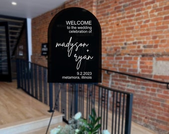 May include: Black arch-shaped sign with white text that reads "Welcome to the wedding celebration of Madyson + Ryan 9.2.2023 Metamora, Illinois".