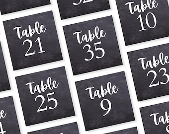 May include: Black chalkboard table number cards with white text. The numbers on the cards are 8, 32, 21, 35, 10, 25, 9, 23. The text on the cards reads "Table".