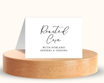 May include: White card with black text that reads "Roasted Corn" with "With Poblano Peppers & Onions" underneath.