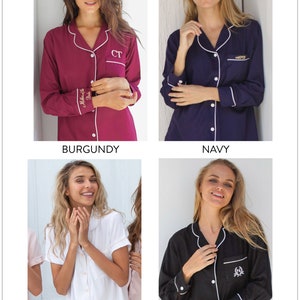 May include: Four women model different colours of pyjamas. The pyjamas are long-sleeved and have a white piping detail. The colours are burgundy, navy, white, and black. The white pyjamas have a short sleeve.