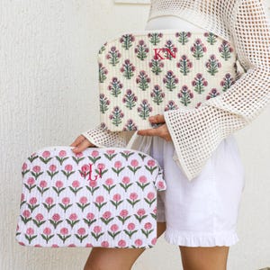 Puede incluir: Dos neceseres con estampados florales. El neceser m&aacute;s grande es de color blanco roto con un dise&ntilde;o floral rosa y verde y las iniciales "KN" en rojo. El neceser m&aacute;s peque&ntilde;o es blanco con un estampado floral rosa y las iniciales "JL" en rojo.