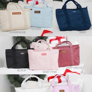 May include: Ten cotton canvas tote bags in various colors, including champagne, tiffany blue, navy, black, baby pink, deep mauve, white, and lilac. Each bag has a small leather patch with the word "CARAT" on it.