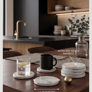 May include: A set of four round Wonder White marble coasters, each measuring 4 inches in diameter. The coasters feature a natural white stone surface with grey veining, shown supporting a clear glass with ice and a black ceramic mug.