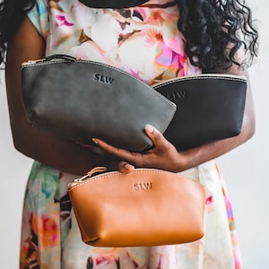 May include: Three leather zippered pouches in black, gray, and brown. Each pouch has the initials "SLW" embossed on the front.