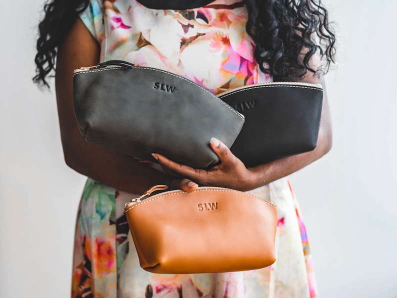 May include: Three leather zippered pouches in black, gray, and brown. Each pouch has the initials "SLW" embossed on the front.
