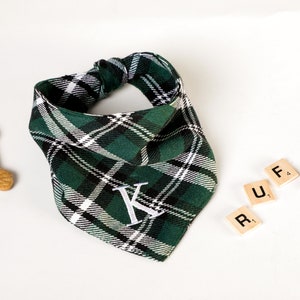 Pu&ograve; includere: Un bandana per cani a quadri verdi e bianchi con una lettera K bianca ricamata. Il bandana &egrave; legato intorno al collo di un cane. La parola "RUFF" &egrave; scritta con tessere di lettere.