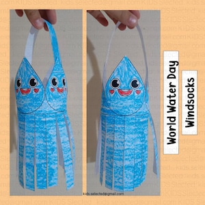 Puede incluir: Una gota de agua de papel azul con una cara sonriente y corazones rojos. La gota de agua tiene una franja de tiras de papel azul. La artesanía está etiquetada como "Día Mundial del Agua" y "Calcetines de viento".