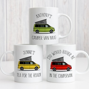 May include: Three white ceramic mugs with personalised text and illustrations of camper vans. The mugs feature the names "Anthony's", "Jennie's", and "Stu Would Rather Be". The vans are green, yellow, and red.