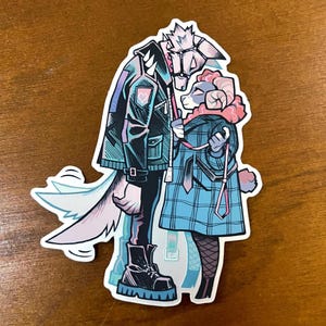 May include: A sticker depicting two animal figures in a close embrace. One is a wolf in a black jacket and boots, the other a ram in a blue plaid coat. A third animal figure is visible in the background. The sticker has a white border.