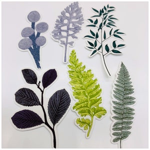 Puede incluir: Un conjunto de seis pegatinas bot&aacute;nicas con diferentes hojas y flores. Las pegatinas est&aacute;n impresas en tonos de verde, azul y morado.
