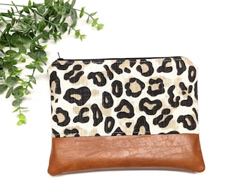 May include: A small leopard print zippered pouch with a brown faux leather bottom.