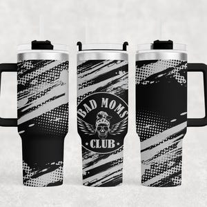 Può includere: Un bicchiere in acciaio inossidabile nero e argento con un manico nero. Il bicchiere presenta un design grafico di pennellate bianche e un teschio con il testo "Bad Moms Club".