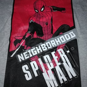 May include: Grey t-shirt with a Spider-Man graphic in red and black. The design includes the words "FRIENDLY NEIGHBORHOOD SPIDER-MAN" in white and grey text against a red and black background.