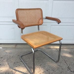 May include: A chrome and wood cantilever chair with a woven cane seat and back.