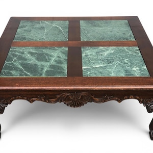 May include: A square coffee table featuring a dark brown wooden frame with four inset green marble tiles. The table has carved wooden aprons and four legs ending in ball and claw feet, showcasing a detailed wood grain and polished finish.