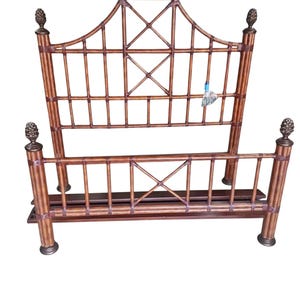 May include: A brown bamboo bed frame with a decorative headboard. The headboard features an arched top with an X-shaped design and vertical and horizontal slats. The bed frame has four posts topped with pineapple finials and a footboard with a similar design.