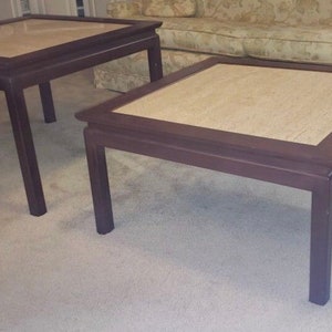 May include: Two square end tables with a light brown marble top and dark brown wood frame.