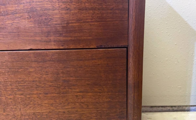 May include: Close-up of a wooden dresser with two drawers. The drawers are made of a rich, dark wood with a smooth finish. The dresser has a simple, classic design.