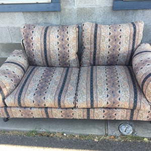 May include: A brown and beige striped sofa with a geometric pattern. The sofa has a metal frame and is in good condition.