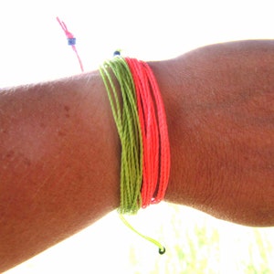 Peut inclure: Un bracelet d'amitié vert et rose sur le poignet d'une personne.